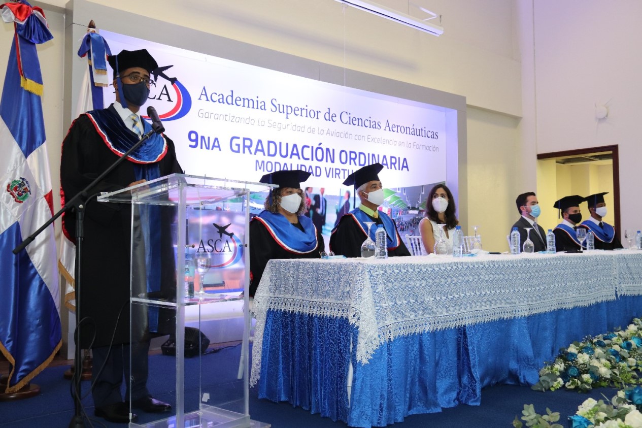 Director de la ASCA, Juan César Thomas Burgos, durante el discurso central. A su lado, los miembros del Claustro Académico, la representante del director general del IDAC, Román Ernesto Caamaño Vélez, Priscilla Camarena y el representante de Aerodom, Luis José López Mena.